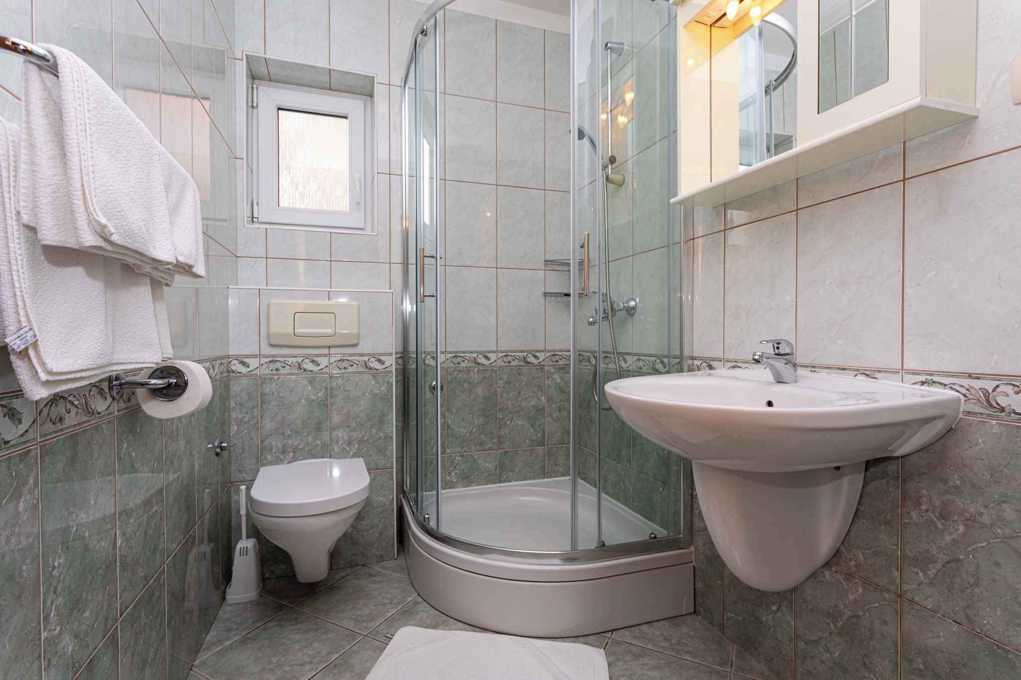 Ein modernes Badezimmer mit einer Duschkabine, einem Standwaschbecken, einer Toilette und einem Handtuchhalter.