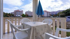 En terrasse med et bord og stole, en blå parasol og udsigt til bygninger og bjerge.