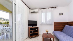 Uma sala de estar com sofá, rack para TV e uma pequena mesa.