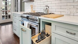 A modern kitchen with white subway tiles, a stainless steel stove, and wooden shelves. - EXPO Oasis-Heart of Tulsa! (Tulsa)