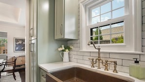 A kitchen with a large sink, white cabinets, and a window above the sink. - EXPO Oasis-Heart of Tulsa! (Tulsa)