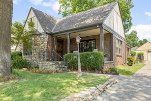 A two-story house with a stone facade, a covered porch, and a front yard with a lamp post. - EXPO Oasis-Heart of Tulsa! (Tulsa)