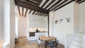 Eine moderne Küche mit weißen Schränken, einem Holztisch und einer Treppe.