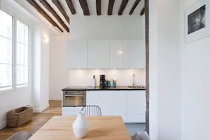 Cozinha moderna com armários brancos, bancada preta e teto de madeira.