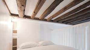 Ein Schlafzimmer mit einem Bett, weißen Wänden und einem Holzbalken an der Decke.