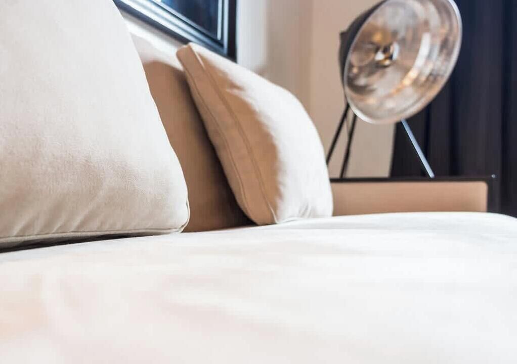 A bed with pillows and a bedside lamp.