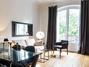 Una sala de estar moderna con una mesa de centro de vidrio, un sofá, una silla y una lámpara de pie.