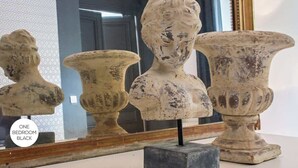 Three antique vases with a weathered finish, displayed on a white surface with a mirror in the background.
