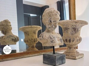 Three antique vases with a weathered finish, displayed on a white surface with a mirror in the background.
