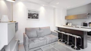 A modern living room with a grey sofa, a coffee table, and a bar area with stools.