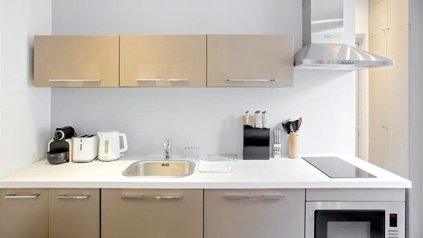 A modern kitchen with a white countertop, stainless steel appliances, and beige cabinetry.