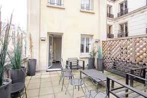 A courtyard with outdoor seating, potted plants, and a wooden lattice wall.