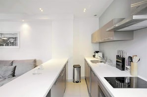 A modern kitchen with white countertops, stainless steel appliances, and a minimalist design.