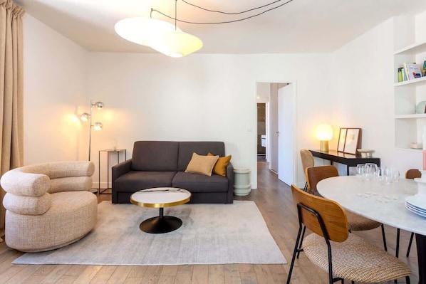 Un salon moderne avec un canapé, une table basse ronde et une table à manger pour quatre personnes.
