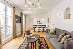 Ein modernes Wohnzimmer mit Sofa, Sessel, Couchtisch und einem Essbereich mit einer Bank und Stühlen.