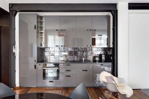 Cozinha moderna com uma ilha grande, eletrodomésticos de aço inoxidável e painel de parede em mármore.