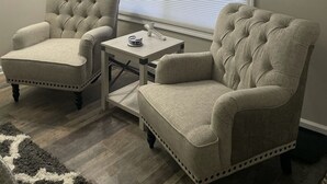 A room with two tufted armchairs, a small table, and a floor lamp. - Adventure Acres- Suite C8  (Holly)