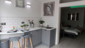 Una cocina moderna con una isla central, taburetes de bar, un lavamanos y un comedor con una cama.