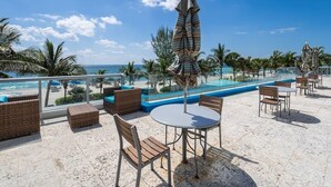 Eine Dachterrasse mit Pool, Liegestühlen und Tischen mit Blick auf den Ozean.