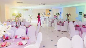 A banquet hall with round tables set for a formal event, white chairs, and floral centerpieces. - Korkdam Hotel (Accra)