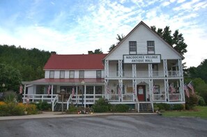 A two-story building with a porch and a sign that reads 'Nacookee Village Antique Mall.'