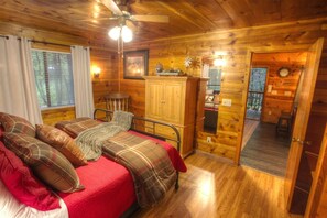 Een knus slaapkamer in een houten chalet met een bed, een kledingkast en een klein bureau.