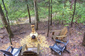 A rustic outdoor seating area with a central fire pit surrounded by wooden chairs and tables.
