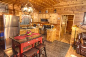 A wooden cabin interior with a kitchen, a dining area, and a seating area.