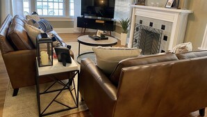 A living room with a sofa, a coffee table, a TV, and a fireplace.