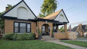 A two-story house with a brick facade, a front porch, and a small garden.
