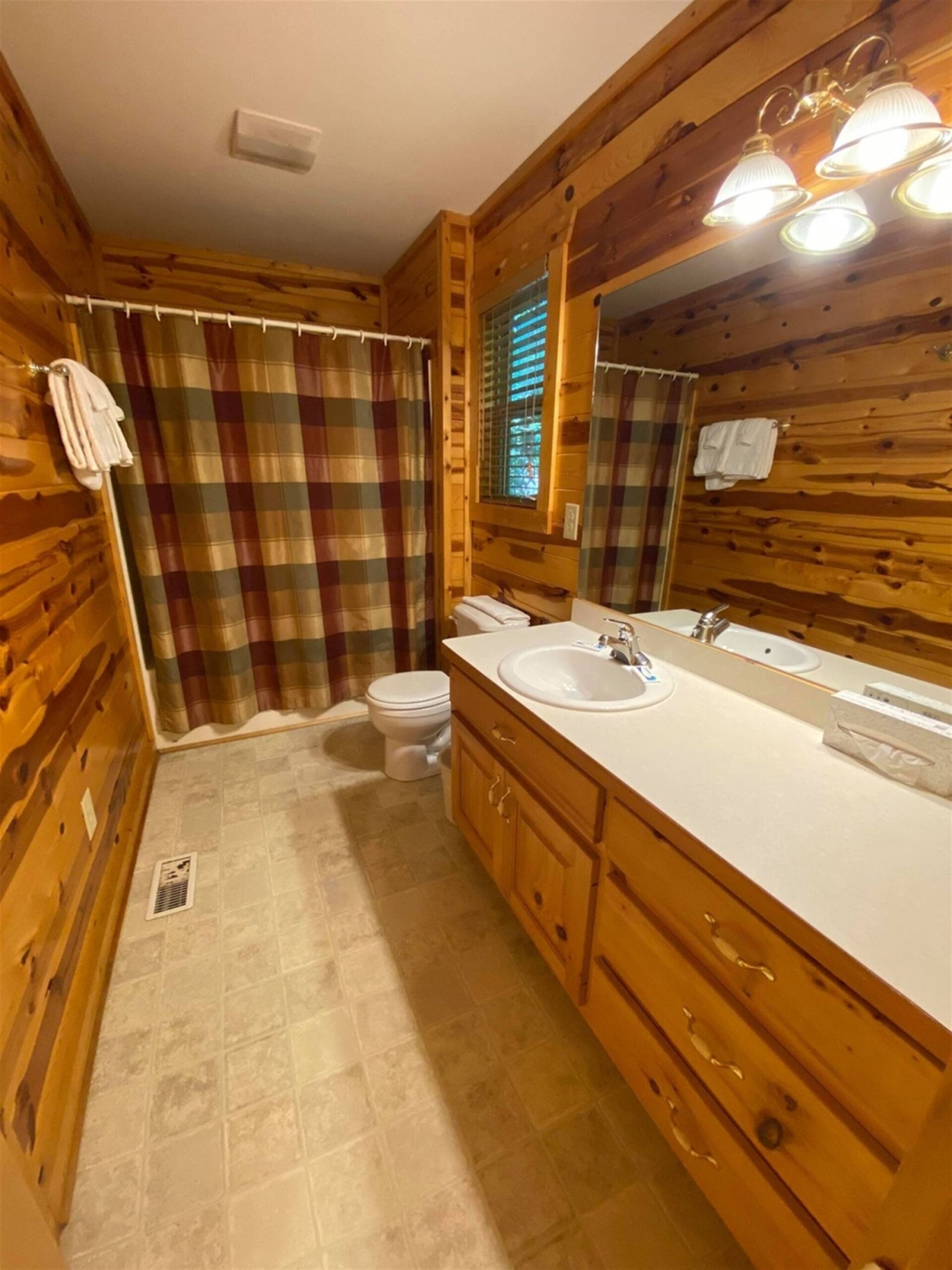 Une salle de bain rustique, aménagée dans une cabane en bois, avec des toilettes, un lavabo et un miroir.