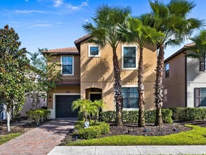 A two-story residential building with a beige facade, a red-tiled roof, and a front entrance with a garage. - 6 BR Villa w/Private Pool + Hot Tub + Lazy River in Gated Resort near Clubhouse (Davenport)