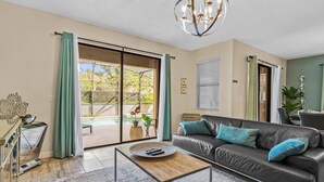 Ett modernt vardagsrum med en soffa i läder, ett soffbord och ett stort fönster med utsikt över en pool.