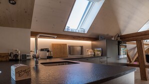A modern kitchen with a skylight, a built-in oven, and a large island with a sink. - NEW - renovated Bitzi - with a view (Appenzell)