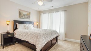 Une chambre à coucher avec un lit, des tables de chevet, un ventilateur de plafond et un tableau au mur.
