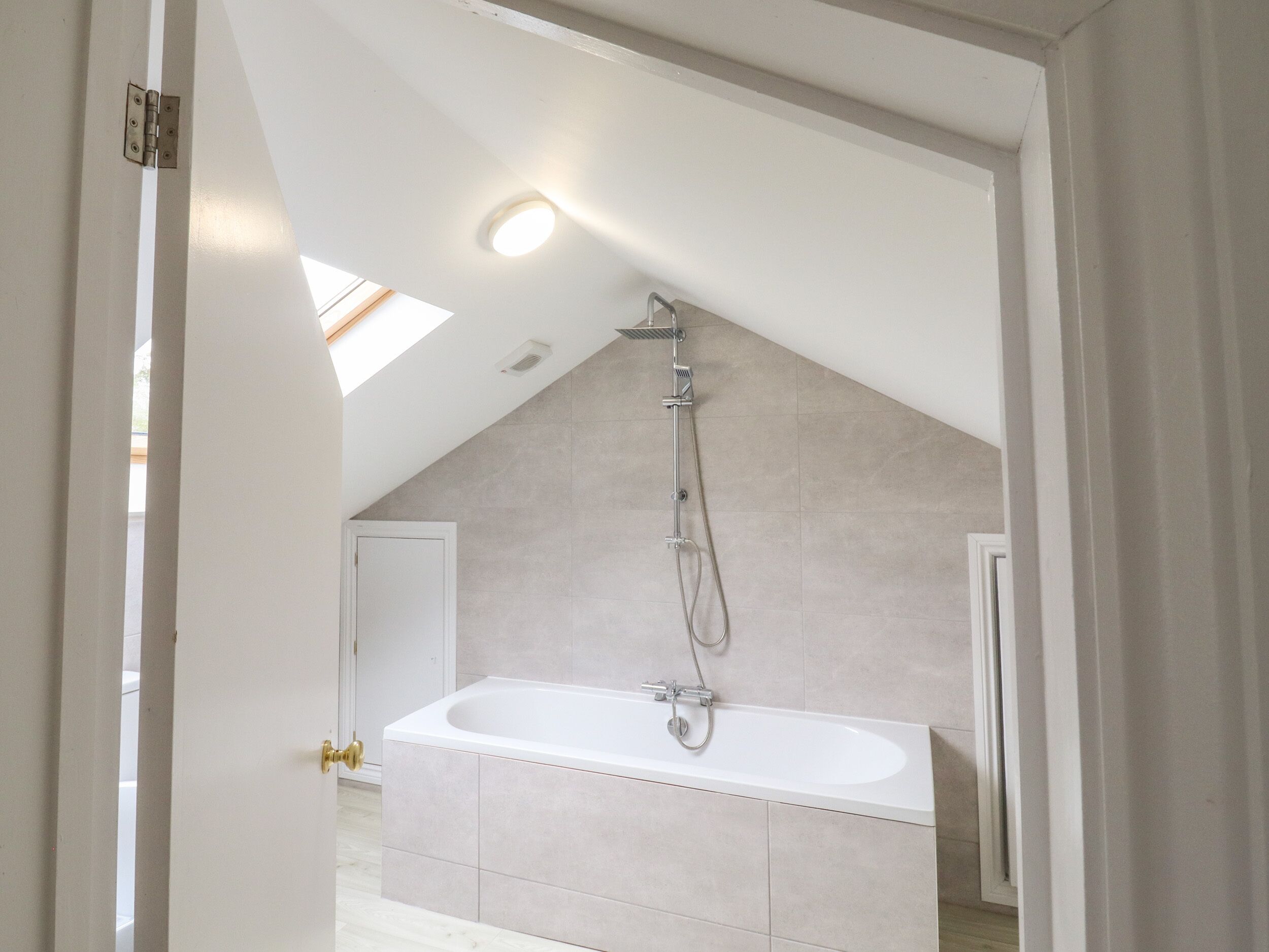 A modern bathroom with a freestanding bathtub, a showerhead, and a skylight.