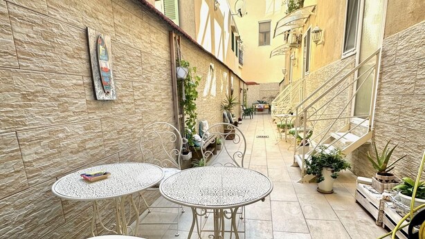 A narrow alley with two round tables and chairs, potted plants, and a staircase. - Astonishing Studio for 2 people in the Heart of Naples 3P (Napoli)