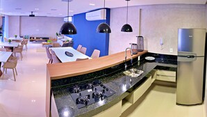 A modern kitchen with a built-in stove, a stainless steel refrigerator, and pendant lighting. - Vacanze - Smart (Maceió)