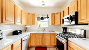 A modern kitchen with wooden cabinets, a stainless steel stove, a microwave, and a toaster. - 5 mins to best of ATX, Stocked kitchen, 4BR 2.5BA, Backyard, Grill, yard games (Austin)