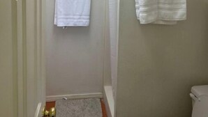 Un bagno piccolo e stretto con pareti bianche, un water bianco e due asciugamani bianchi appesi a un portaserviti.