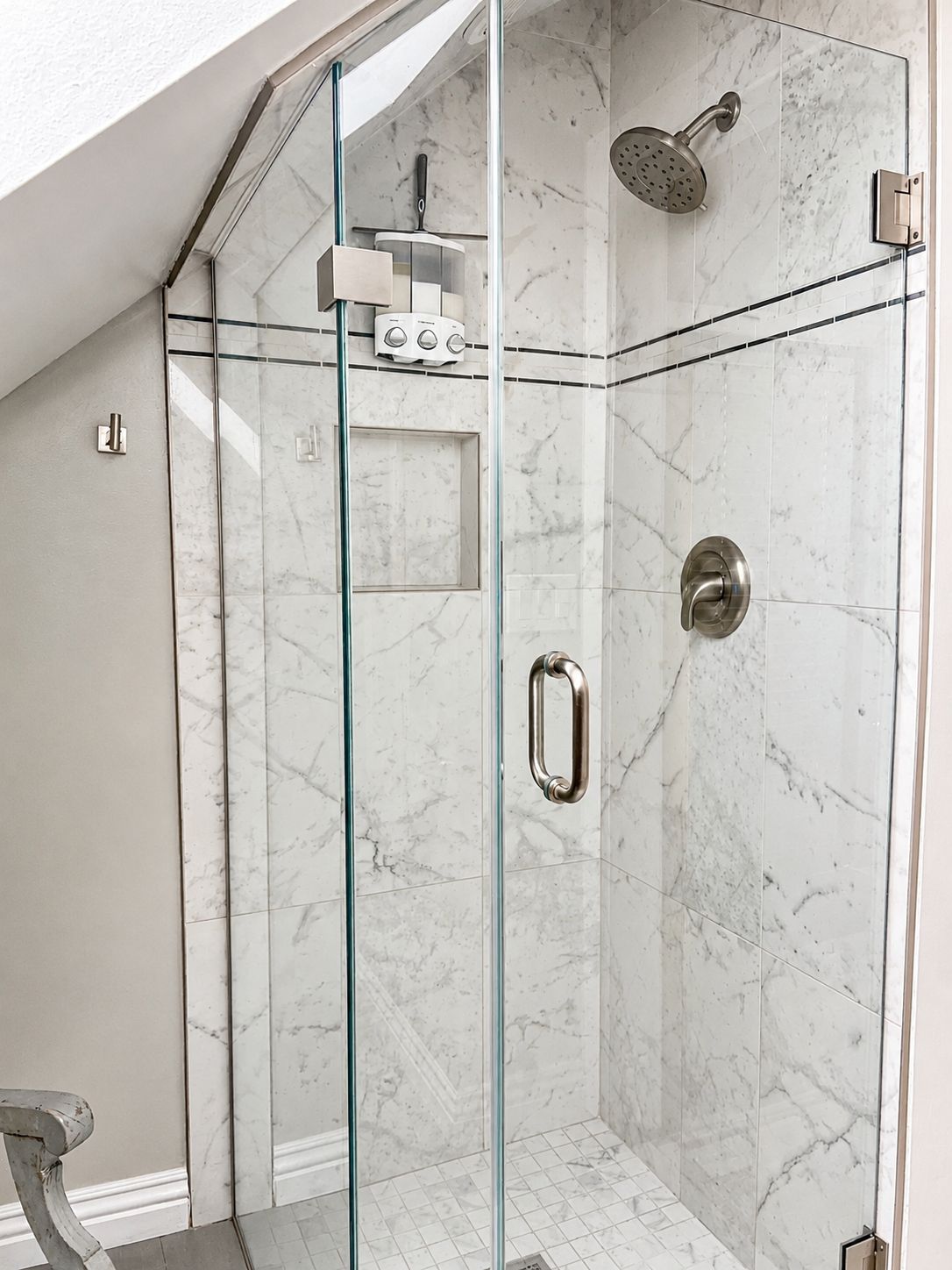 A modern shower with glass doors, a handheld showerhead, and a wall-mounted control panel.