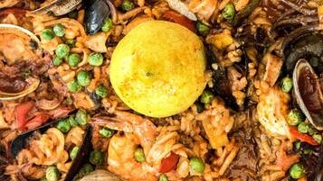 Primer plano de una paella de mariscos con guisantes y una rodaja de limón.
