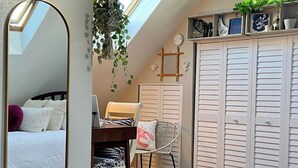 Ein Schlafzimmer mit Dachfenster, einem Bett, einem Schreibtisch mit Stuhl und einem Kleiderschrank.