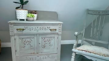 A white dresser with floral patterns and two potted plants on top.