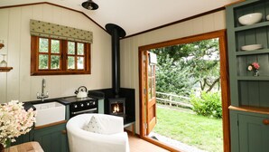 A cozy kitchen with a built-in stove, wooden cabinets, and a window overlooking a garden. - Little Silver Pheasant (Umberleigh)