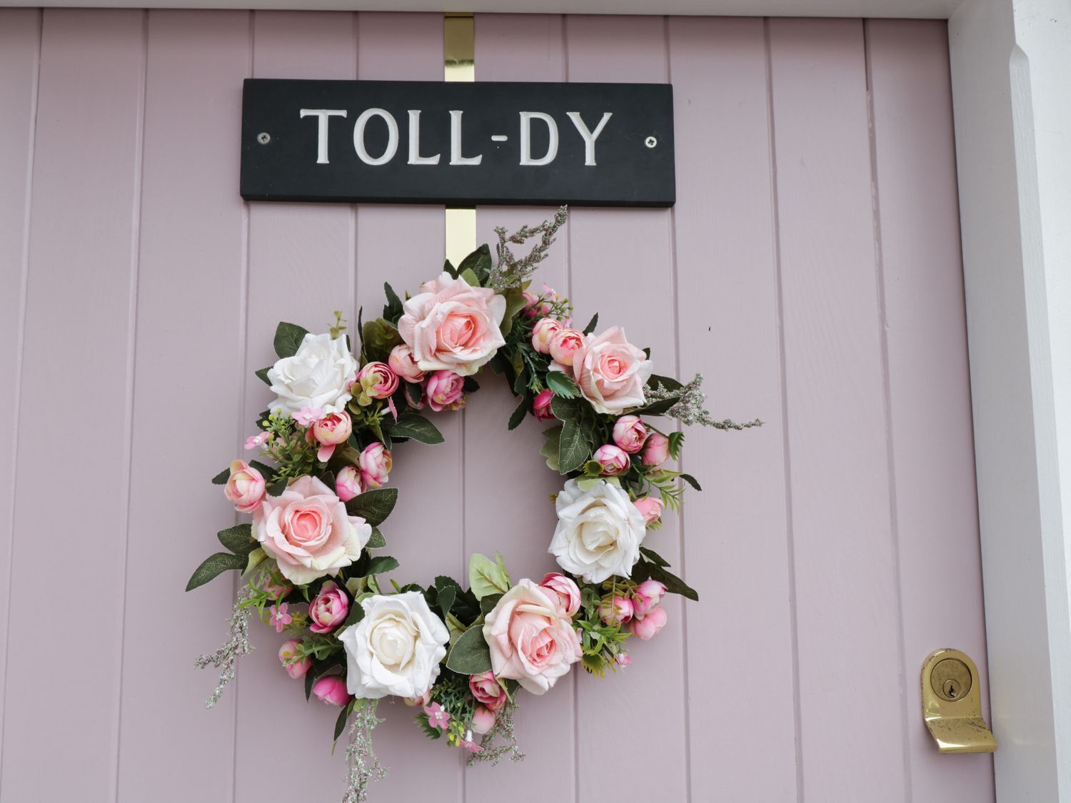 Una puerta con un letrero 'TOLL-DY' y una corona de flores.