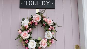 Una puerta con un letrero 'TOLL-DY' y una corona de flores.
