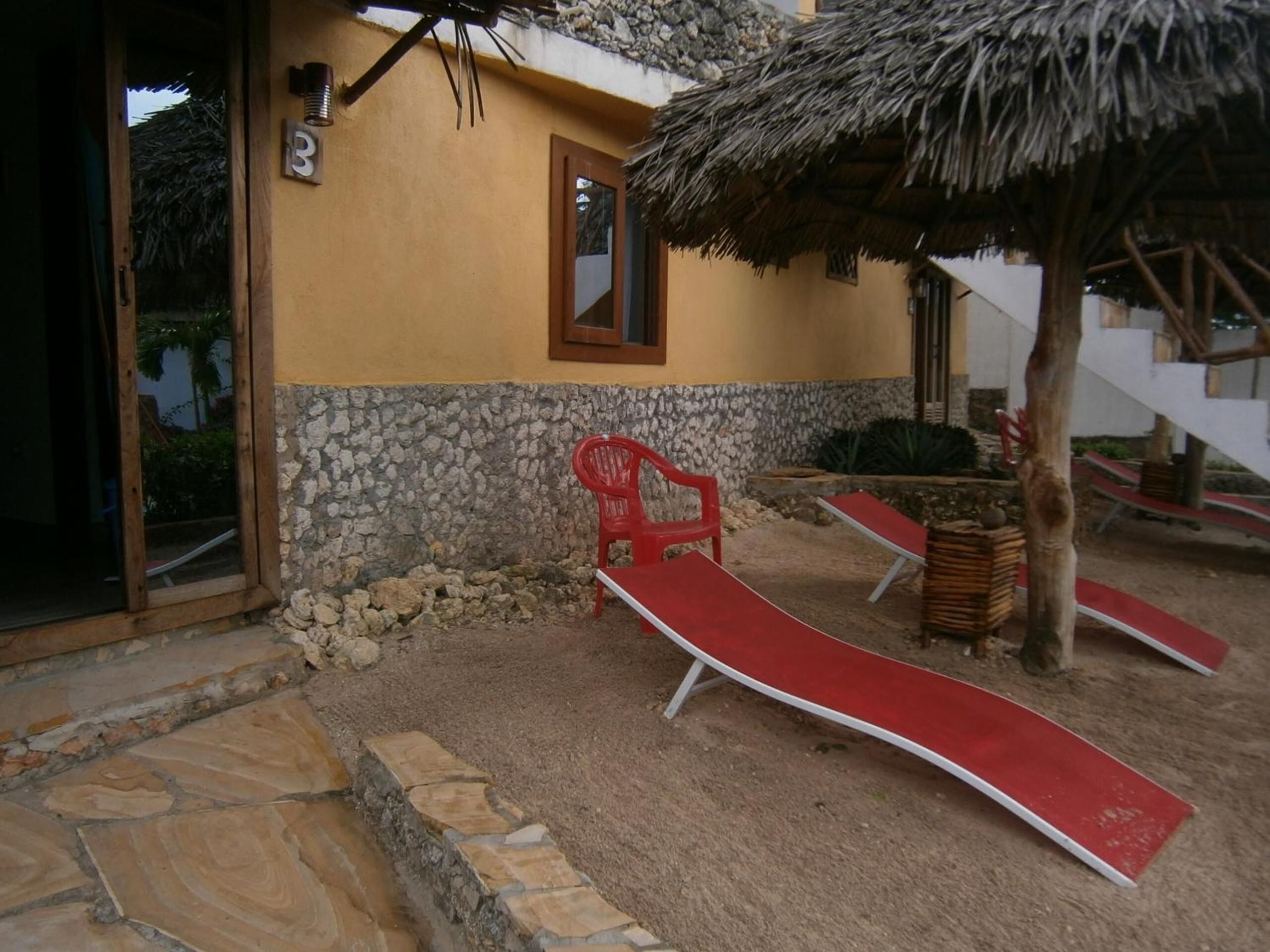 A building with a stone wall, a thatched roof, and a red chair.
