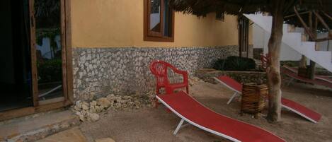 A building with a stone wall, a thatched roof, and a red chair.