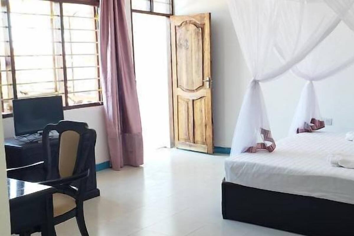 A hotel room with a bed, a desk, and a chair.